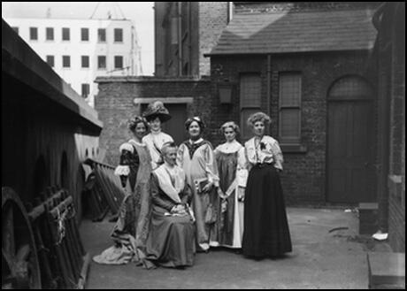 Teresa Billington-Greig is standing in the centre next to Charlotte Despard who is sitting down.