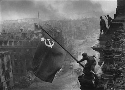 Soldiers raising the flag of Soviet Union on the roof of Reichstag building in Berlin.
