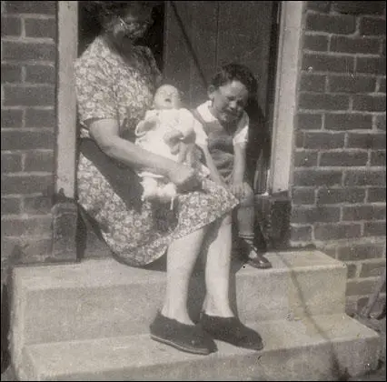Eleven week old David Simkin in the arms of his maternal grandmother Elizabeth Hughes. Sitting alongside Mrs Hughes and Muriel's baby son is David's older brother John Simkin. This photograph was taken in the back garden of the Simkin family home at 42 Bernwell Road, Chingford, Essex in 1949.
