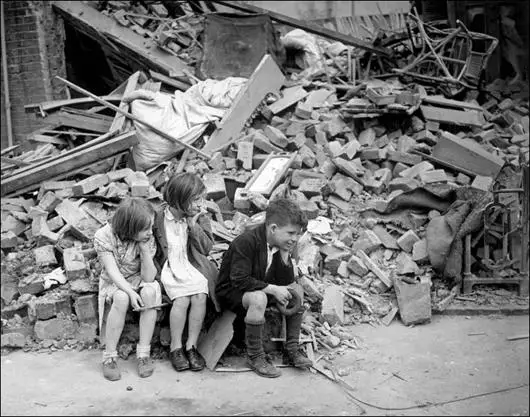 Three children sit in front of their remains of their home in the East End (September, 1940)