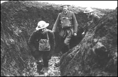 Officers walking through a flooded communication trench.