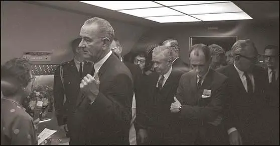 Photograph of a group waiting for the arrival of Jackie Kennedy for the swearing in ceremony. Left to right: Judge Sarah T. Hughes, Lyndon B. Johnson, Evelyn Lincoln, (background), Homer Thornberry, Jack Brooks (arms folded), Cliff Carter and Bill Moyers.