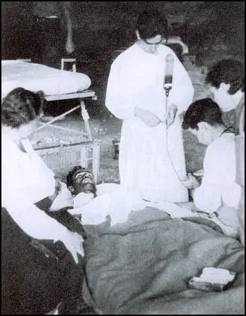 Harry Dobson receiving a blood transfusion fromReginald Saxton while receiving support from Leah Manning.